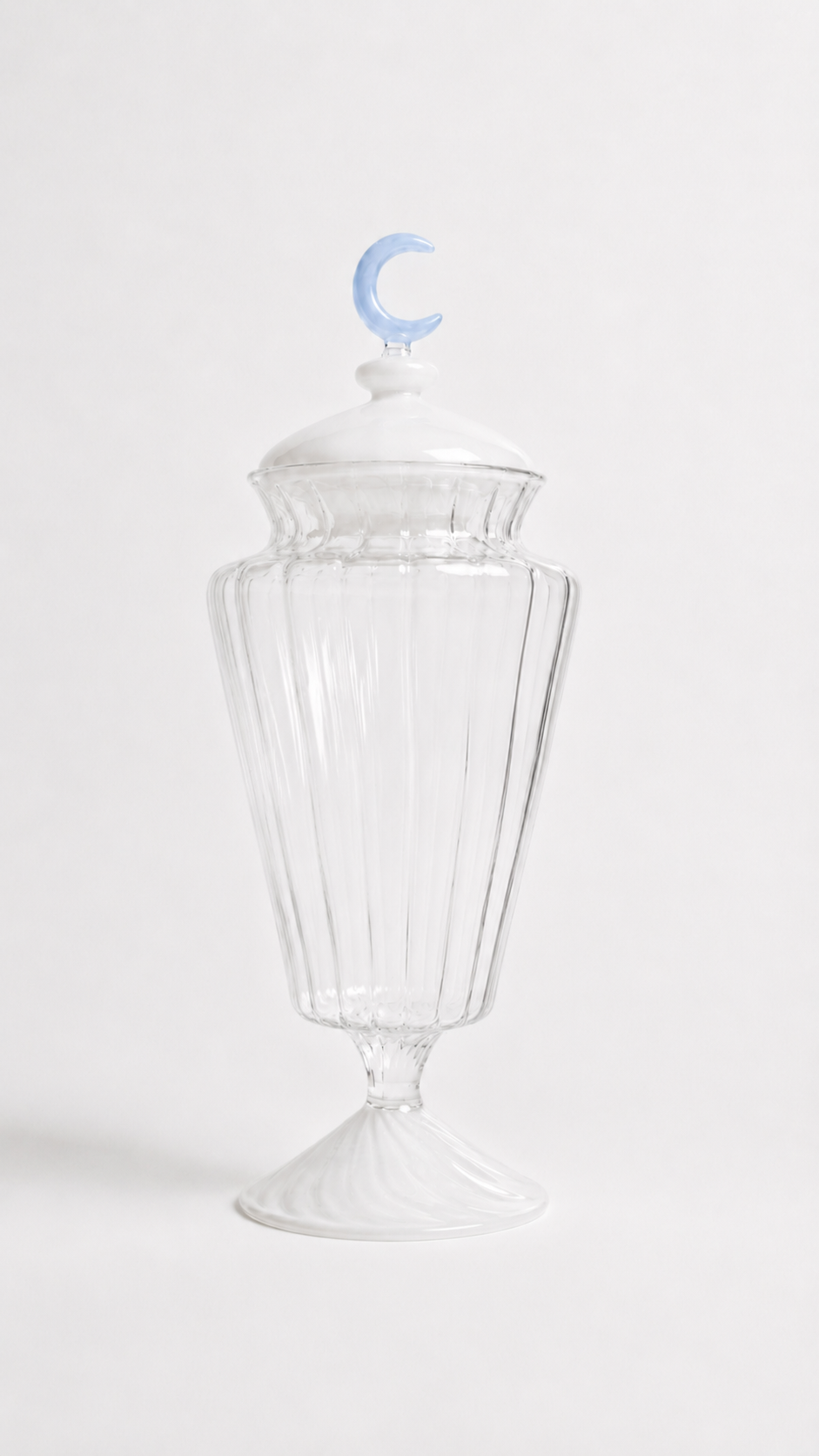 Transparent blown glass candy jar with a blue crescent moon lid inspired by traditional Ramadan fanoos lanterns, isolated on a white background.