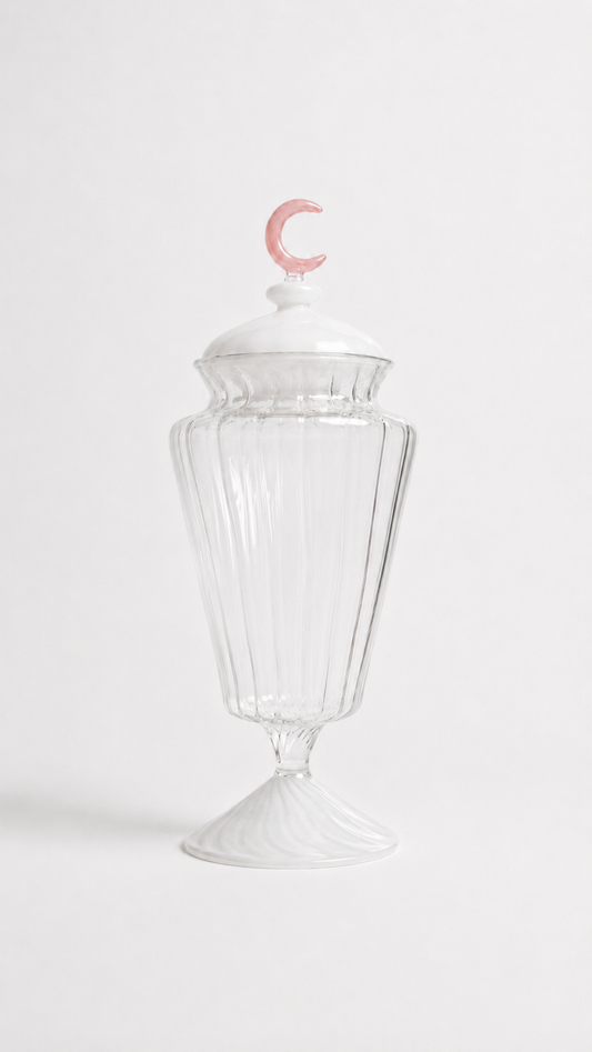 Transparent blown glass candy jar with a pink crescent moon lid inspired by traditional Ramadan fanoos lanterns, isolated on a white background.